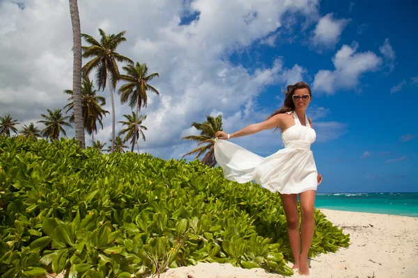 Young beautiful female model in white dress on Caribbean beach — Stock Photo, Image