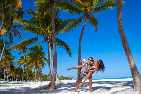 Muž dává piggyback jízda na přítelkyni na pláži — Stock fotografie