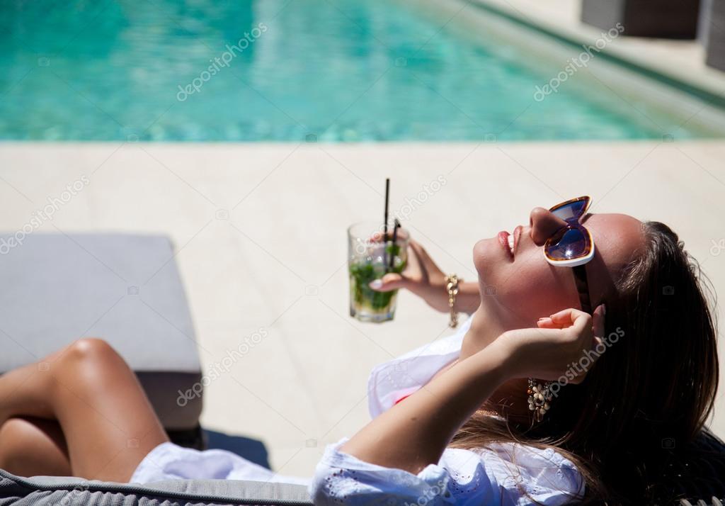 sexy girl with a cocktail near the pool
