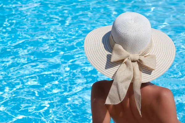 Mujer joven sentada en la repisa de la piscina — Foto de Stock