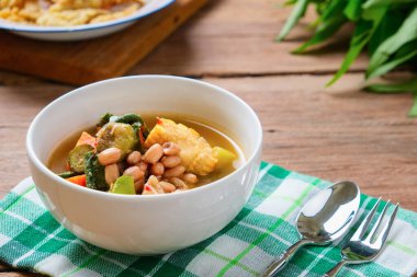 Sayur asam, beyaz kaseyle ahşap masa arkaplanının üzerine yakın dur. Tipik Endonezya mutfağı