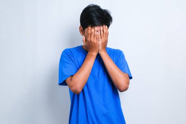 Bıyıklı Asyalı bir adam ağlarken suratını ellerle kapatan üzgün bir ifade takınıyor. Beyaz arkaplan üzerinde depresyon kavramı