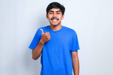 İzole edilmiş beyaz arka plan üzerinde duran, sıradan gömlekler giyen genç yakışıklı bir adam mutlu bir el hareketi yapıyor. Kameraya bakıp başarıyı gösteren ifade onaylanıyor.