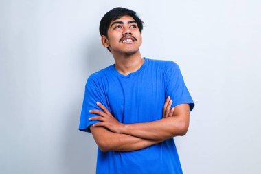 Beyaz arka plan üzerine gündelik tişört giyen genç yakışıklı kollarını kavuşturup kameraya bakarak gülümsüyor. pozitif kişi.