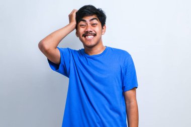 Bıyıklı, sıradan tişörtlü, beyaz arka planda duran yakışıklı genç adam soru sorup kafasını karıştırıyor. Şüpheyle kararsız, kafa kafaya düşünerek. Düşünceli kavram.