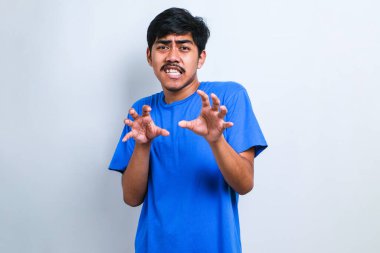 Yakışıklı Asyalı bir adam beyaz arka plan üzerinde sıradan bir tişört giyerek avuçlarını hareket ettiriyor. Korkmuş ve iğrenç bir ifadeyle reddediyor. Dur ve yasakla.