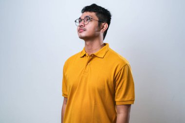 İzole edilmiş beyaz arka plan üzerinde rahat gömlekler giyen genç yakışıklı bir adam yüzünde gülümseme, doğal bir ifade ile diğer tarafa bakıyor.