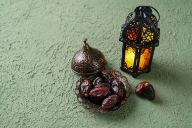 Aydınlatılmış Fas dekoratif lambası ve eski antika bir tabakta hurmalar. Ramazan arkaplan kavramı