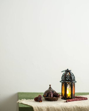 Ramazan Kareem tebrik kartı, davetiye. Fas feneri ve yanan bir mum. Eski ahşap arka planda Türk kasesi üzerine tarihler