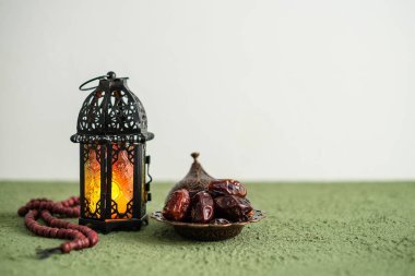 Ramazan Kareem tebrik kartı, davetiye. Fas feneri ve yanan bir mum. Eski ahşap arka planda Türk kasesi üzerine tarihler
