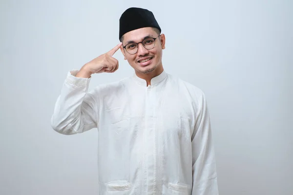 Usmívající Mladý Asijský Muslim Ukazuje Hlavu Prstem Odděleným Přes Bílé — Stock fotografie