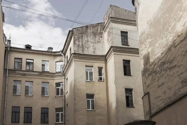 St. Petersburg 'un merkezindeki avluda yürüyüş. Eski bir binanın sarı duvarları.