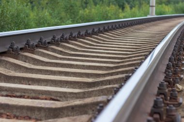 Demiryolu rayları ve pusucular yakın plan. Uzakta bir virajı dönen bir demiryolu..