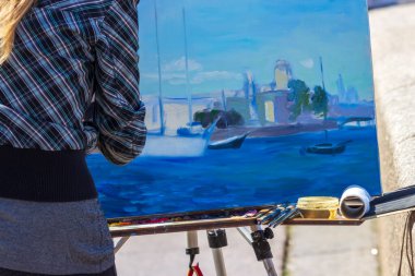 St. Petersburg, Rusya - 24 Temmuz 2021: Sanatçı St. Petersburg 'daki Neva Embankment üzerinde bir manzara çiziyor. Sokakta resim çizen bir kadın..