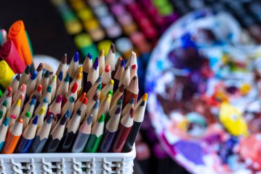 Resim malzemelerinin arka planına karşı bir stantta duran renkli kalemler. Sanatçının masasındaki kalemler..