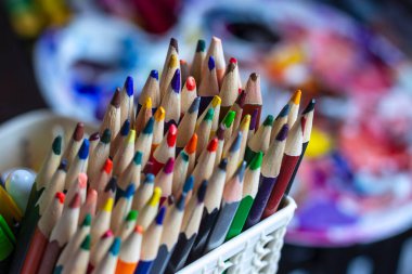 Resim malzemelerinin arka planına karşı bir stantta duran renkli kalemler. Sanatçının masasındaki kalemler..