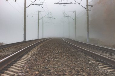 Sonbahar manzarasının ortasında sise karışan bir demiryolu. Demiryolları uzaklarda kayboldu ve sisin içinde kayboldu..