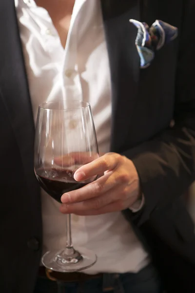 Main tenant un verre de vin rouge dans la fête — Photo