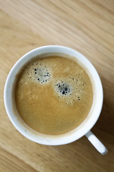 Čerstvá káva v bílých cup na dřevěné pozadí — Stock fotografie