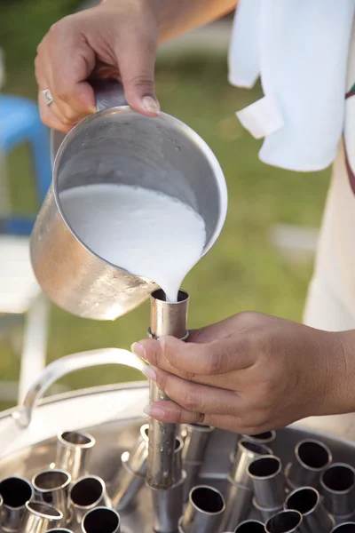 Hand pouring coconut milk into ice cream tube — Stock Photo, Image