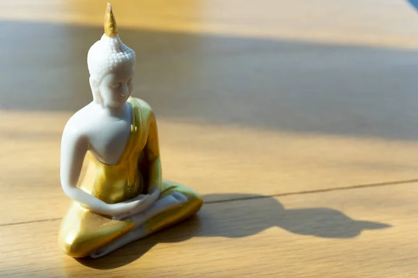 Kleine Buddhistische Statue Auf Holztisch Bei Tageslicht Für Ruhe Und Stockfoto