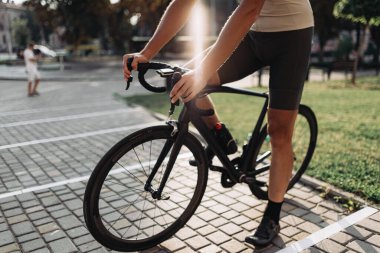 Spor giyim sektöründeki bisikletçilere yakın çekim. Şehir sokaklarında antrenman yapmak için boş vakitlerini harcıyorlar. Arka planda yaz güneşi ışığı. Formda kalmak için düzenli egzersiz.
