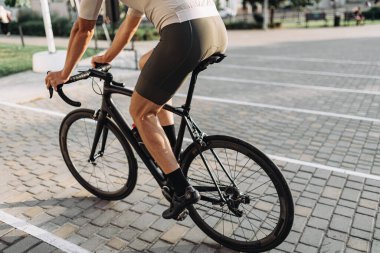 Spor elbiseli bisikletçilerin yaz aylarında dışarıda bisiklet sürmelerini kapatın. Kaslı erkek bacaklarına odaklan. Açık havada egzersiz..