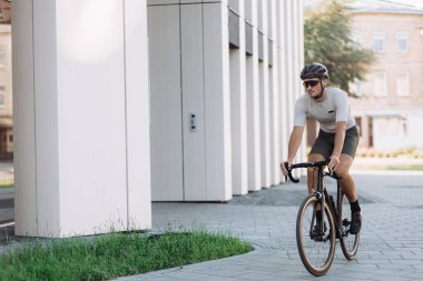 Spor giyim sektöründe boş zamanlarında bisiklet süren sağlıklı beyaz bir adam. Kentsel ortamlarda aktif egzersiz yapan profesyonel bisikletçi.