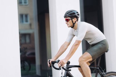 Beyaz tenli sporcu temiz havada bisiklet sürmek için siyah bisiklet kullanıyor. Spor kıyafetler, kask ve gözlük takan sağlıklı bir adam. Etkin yaşam tarzları konsepti.