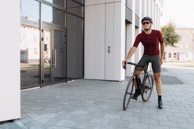 Siyah spor bisikletiyle dışarıda poz veren kaslı kaslı beyaz bir adam. Profesyonel bisikletçi sabah saatlerinde şehirlerarası yolculuktan sonra dinleniyor..