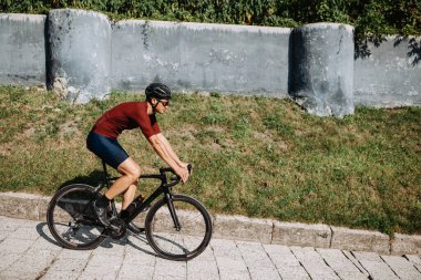 Aktif giysili, kasklı ve gözlüklü bir adamın siyah motosikletle gezintiyi zevkle izlemesi. Kafkasyalı bisikletçi boş zamanlarını en sevdiği hobiye harcıyor..