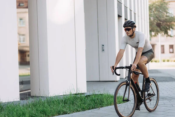 Kasklı ve gözlüklü aktif sporcu şehir sokaklarında siyah bisiklete biniyor. Kafkas adam boş zamanlarında en sevdiği aktif hobiyi yapıyor..