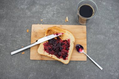Kiraz reçelli ev yapımı ekmek, köy kahvaltısı. Gri masada..