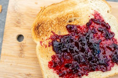 Kiraz reçelli ev yapımı ekmek, köy kahvaltısı. Gri masada..