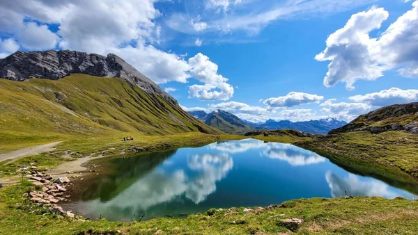 Güneşli bir günde Monzabonsee manzarası. Vorarlberg 'deki Lechtal Alpleri' nde göl. Beyaz bulutlar bir dağ gölünün suyuna yansıyor.