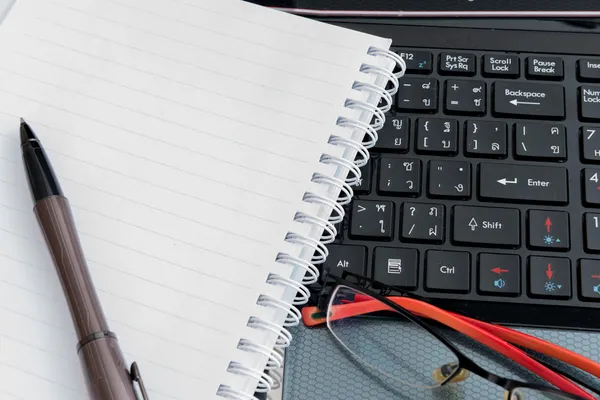 Laptop, penna, anteckningsblock och glasögon — Stockfoto