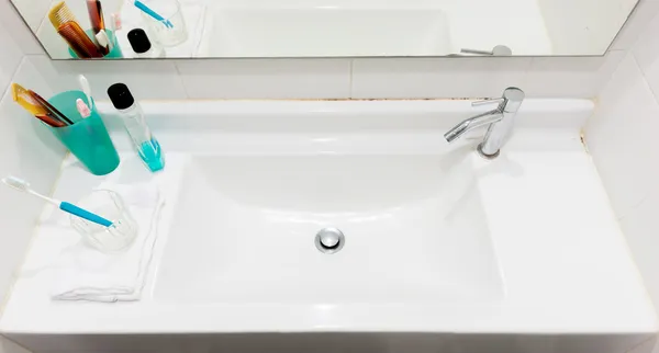 Lavabo con cepillo de dientes y vidrio y peine y gárgaras y toallas a —  Fotos de Stock