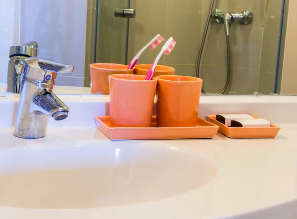 Dos taza de naranja y cepillo de dientes en un lavabo —  Fotos de Stock