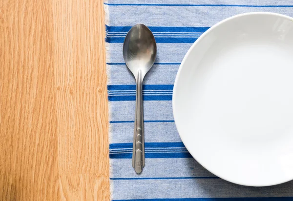 White plate and silver spoon — Stock Photo, Image