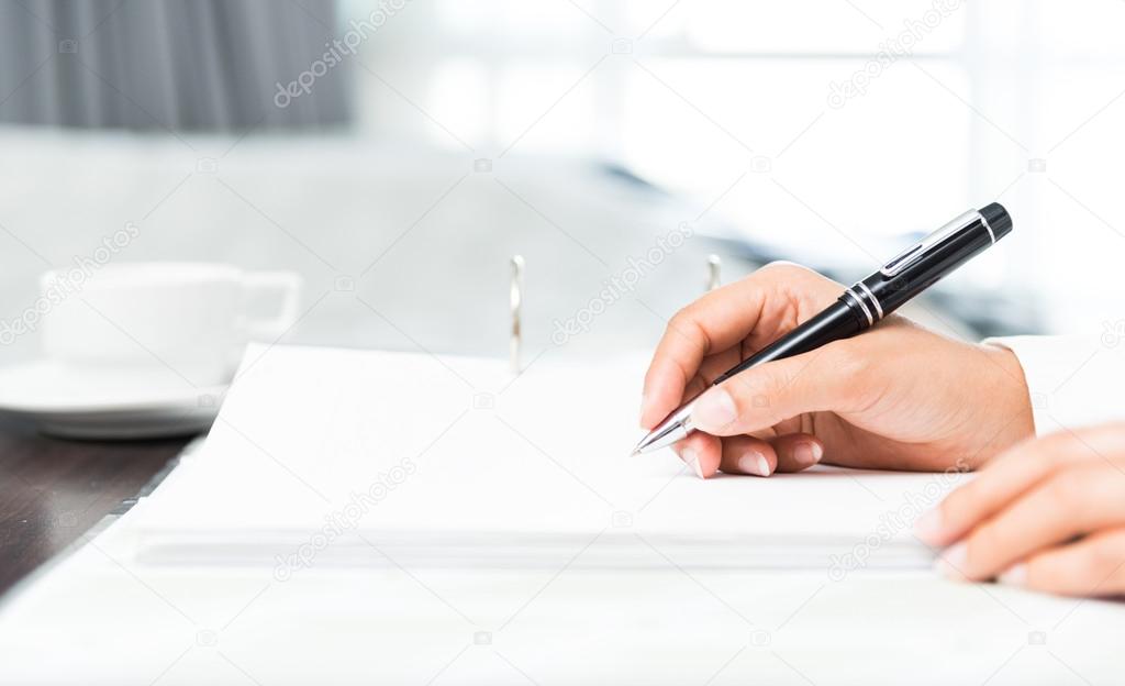 Close shot of a human hand writing something on the paper