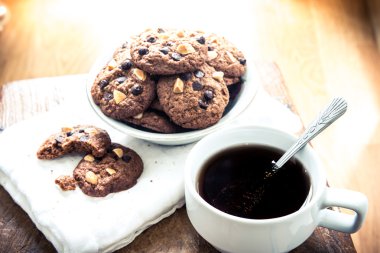 çikolatalı kurabiye peçete ve ahşap masa üzerinde sıcak çay.