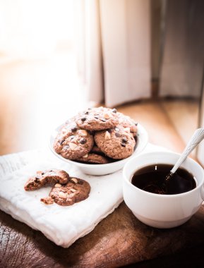 çikolatalı kurabiye peçete ve ahşap masa üzerinde sıcak çay.