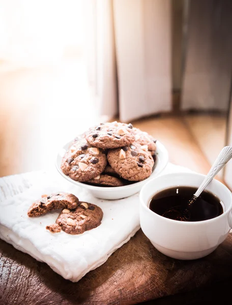 Galletas de chispas de chocolate en servilleta y té caliente en mesa de madera . —  Fotos de Stock