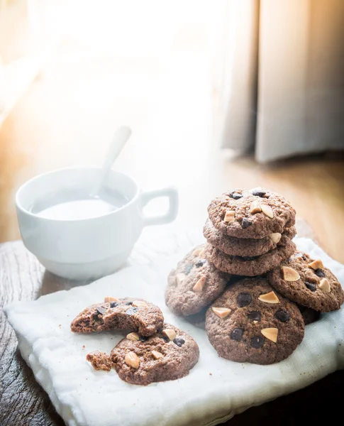 Galletas de chispas de chocolate en servilleta y té caliente en mesa de madera . —  Fotos de Stock