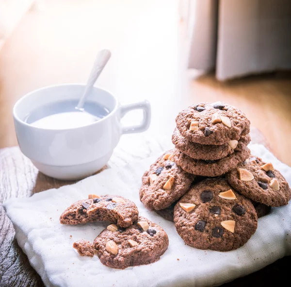 Chocolade chip cookies op servet en hete thee op houten tafel. — Stockfoto