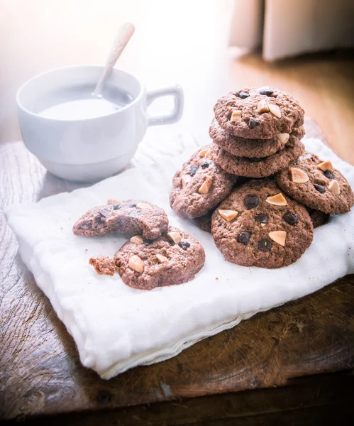 Galletas de chispas de chocolate en servilleta y té caliente en mesa de madera . —  Fotos de Stock