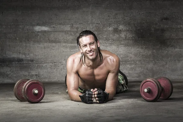 Otot dan atlet tersenyum tergeletak di lantai — Stok Foto