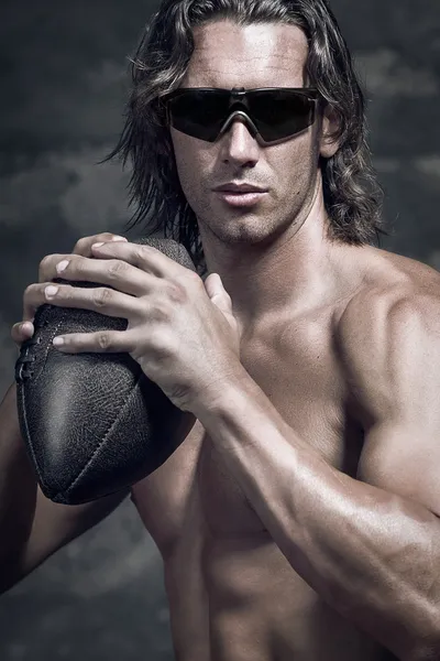 Bare chested muscle man holding football ball in his hands — Stock Photo, Image