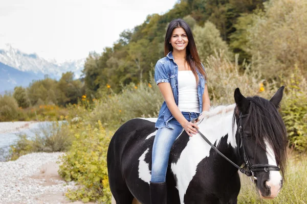 Atının üzerinde oturan ve gülümseyen kadın binici — Stok fotoğraf