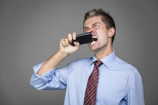 Hombre de negocios muy enojado mordiendo su teléfono móvil — Foto de Stock